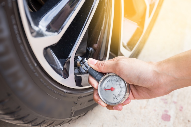 Close-Up Of Hand holding pressure gauge for car tyre pressure measurement