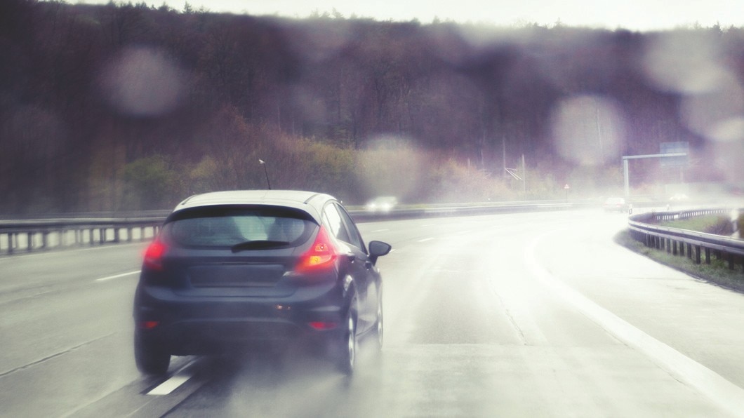 Compact car driving on a wet highway.